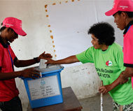 Elections législatives au Timor-Leste. Des agents d'un bureau de vote aident une électrice à mettre son bulletin dans l'urne lors des législatives du 7 juillet 2012. Photo ONU/Martine Perret 
